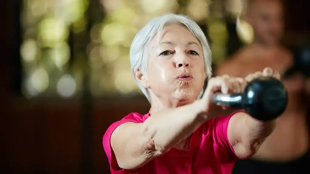 Older woman doing weight training Crewe to help her strength and longevity 