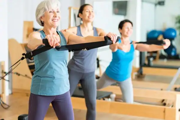 Toning Arms After 60: Empowering Womens Fitness Through Effective Weight Training 2 older woman doing weight training Crewe and resistance in the gym to tone upper arms
