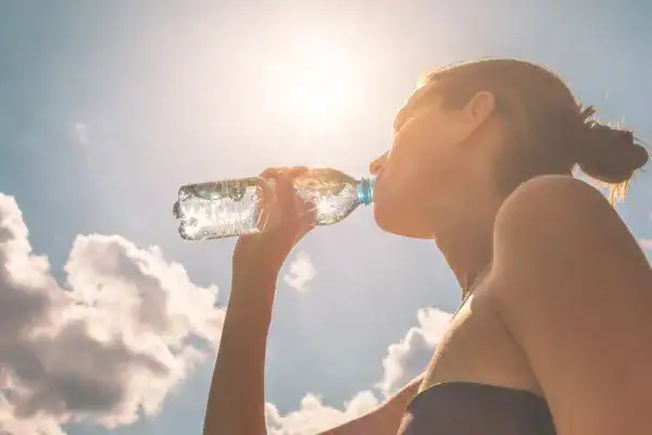 Hydration: The Secret Ingredient for a Toned Stomach and Enhanced Fitness 3 Image of woman drinking water to hydrate Crewe after run.