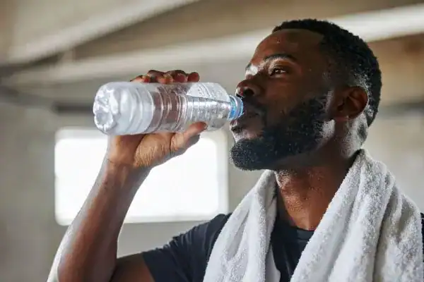 Image of man drinking water to improve hydration Crewe after work out.